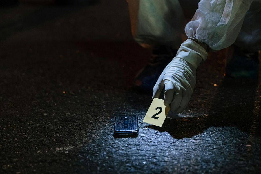 A person collecting a mobile phone as evidence from a crime scene